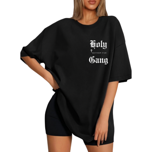 Woman wearing black oversized Holy Gang t-shirt with with white gothic logo, cross and Matthew 17:20 verse. 