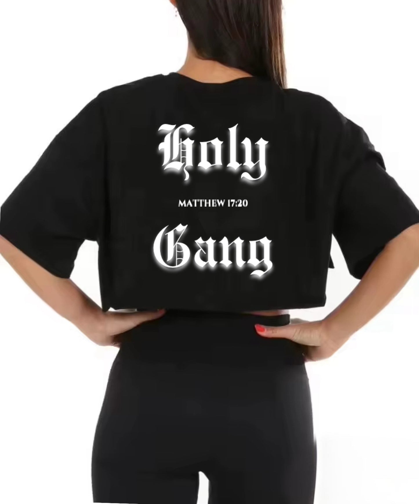 Back view of woman wearing a white cropped t-shirt with bold black gothic text that reads "Holy Gang" and the Bible verse reference 'Matthew 17:20'