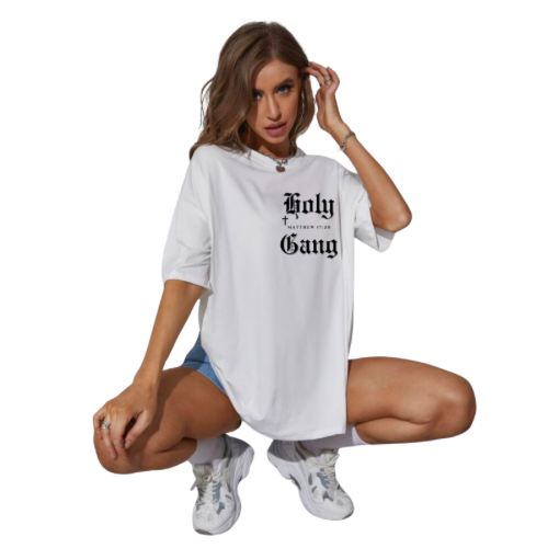 Female model crouching down wearing a white oversized Holy Gang t-shirt with black gothic logo, cross and Matthew 17:20 verse. 